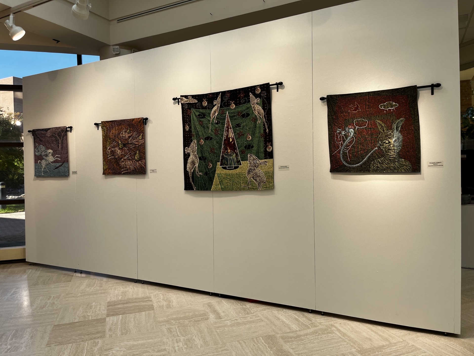 Deetz exhibition wall backside of desk. 3 20 x 20 inch tapestries with one larger tapestery